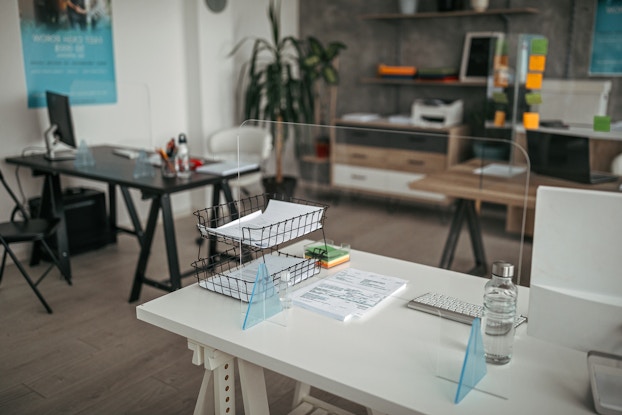 Office space with plastic partitions around each desk.
