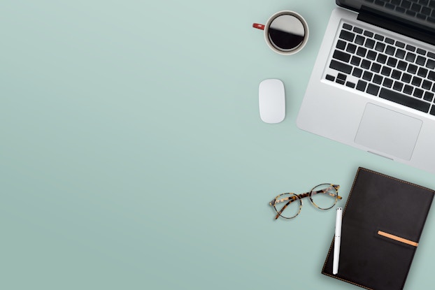 laptop, planner and coffee on a green desk