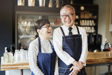  Two entrepreneurs smiling and laughing in their cafe. 