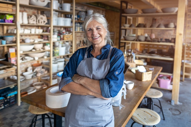 Woman wearing an apron working inside pottery studio.