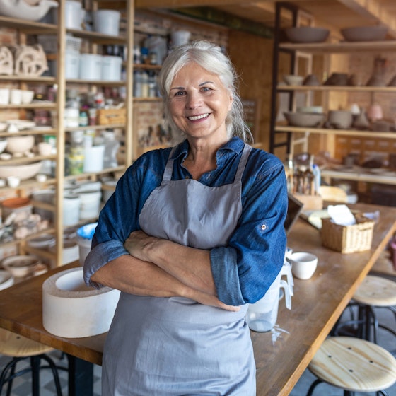 Woman wearing an apron working inside pottery studio.