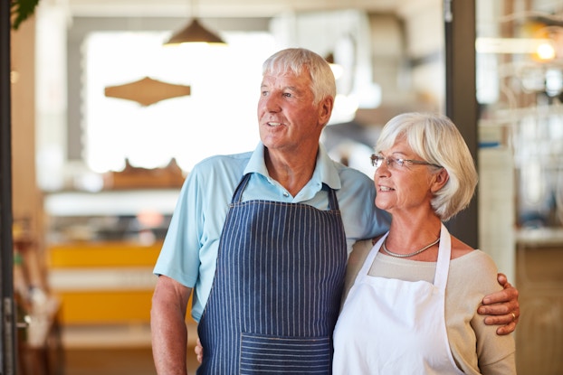 older husband and wife business owners with their arms around each other