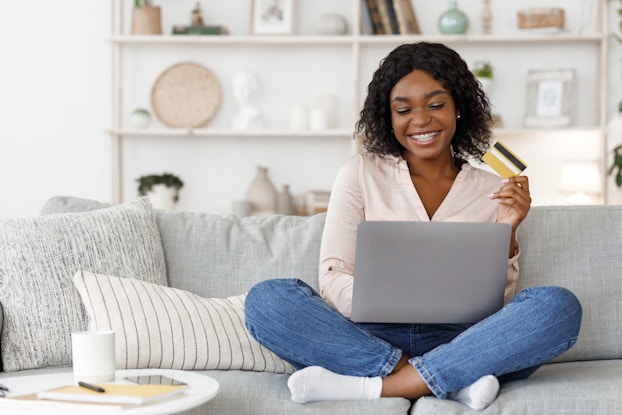  Woman shopping online on her laptop holding a credit card.