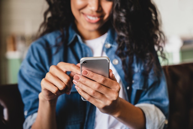  Woman smiling while looking down at her cell phone.