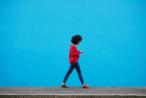  woman walking while on smartphone