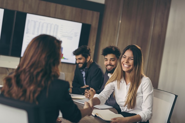 coworkers in a meeting shaking hands