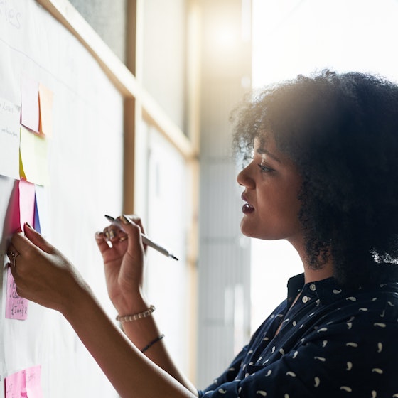 woman working and writing notes on whiteboard