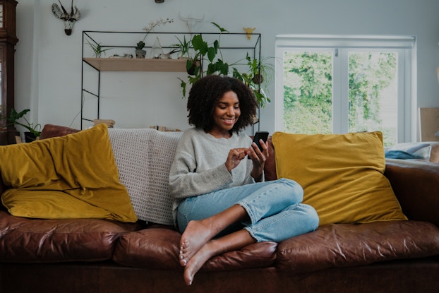 Woman on couch texting on smartphone.
