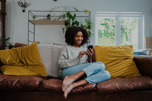  Woman on couch texting on smartphone.