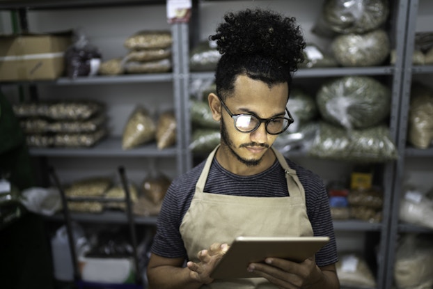  Man uses iPad at his small business to develop his brand.