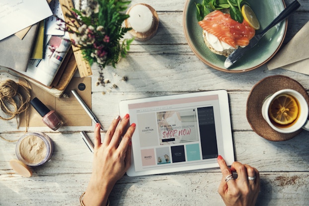 woman using tablet on table with food and coffee