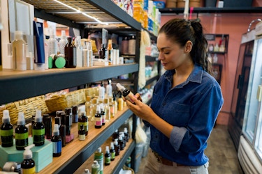  A woman shopping at an organic health food store market reads a product label. 