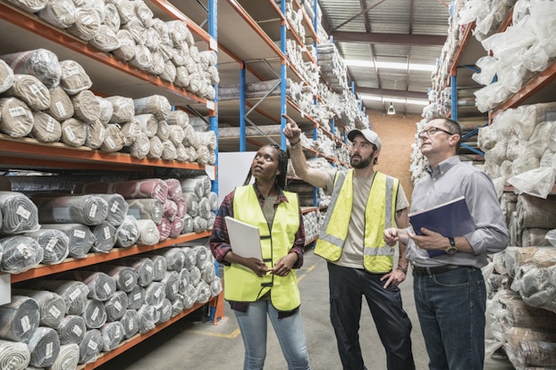 three people in a factory looking at goods on shelves