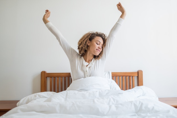  Woman stretching while waking up in bed.