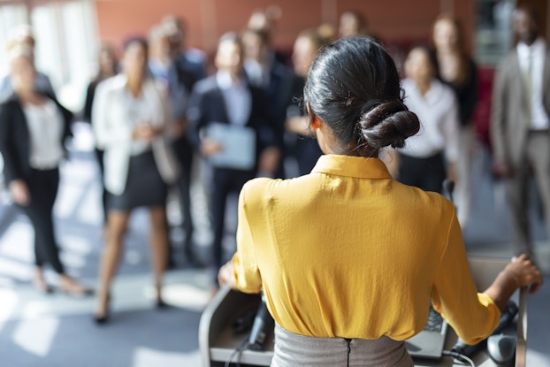  woman speaking to team of colleagues