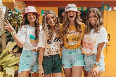  Four Pura Vida models standing in a row smiling and holding up peace signs. 