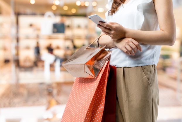  woman holding shopping bags and phone