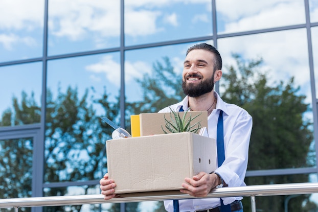 man holding box with office things after quitting job