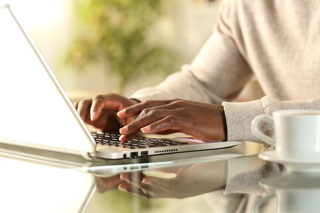  Person's hands typing on laptop.