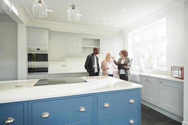A real estate agent shows a couple around a home with new kitchen.