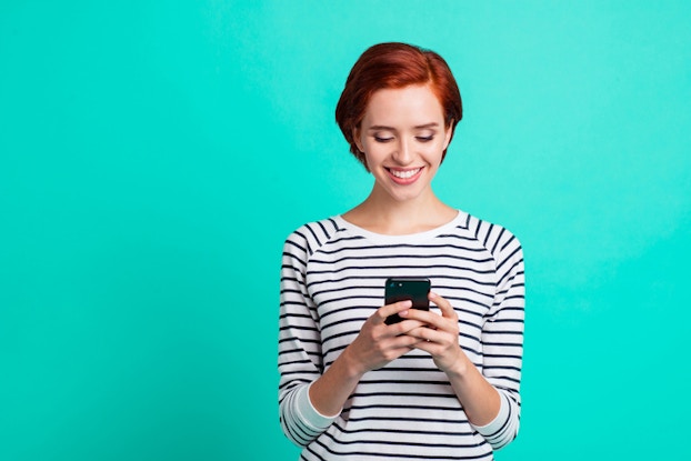 woman smiling while holding phone