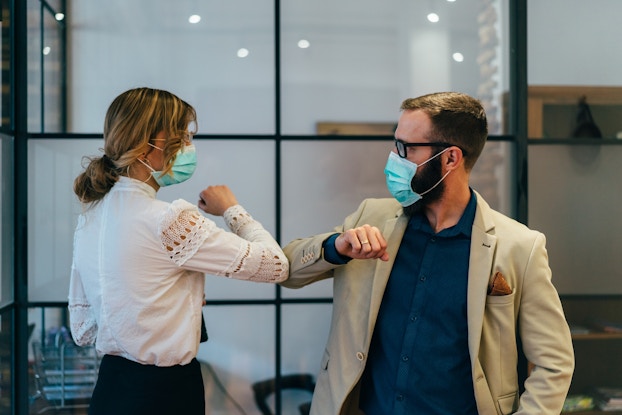  two coworkers with masks bumping elbows