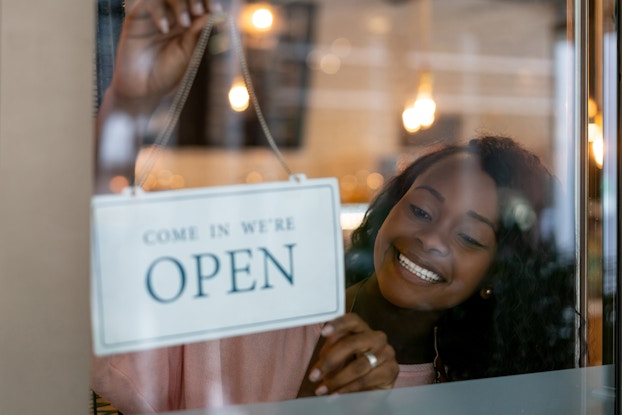  woman holding open sign in business window
