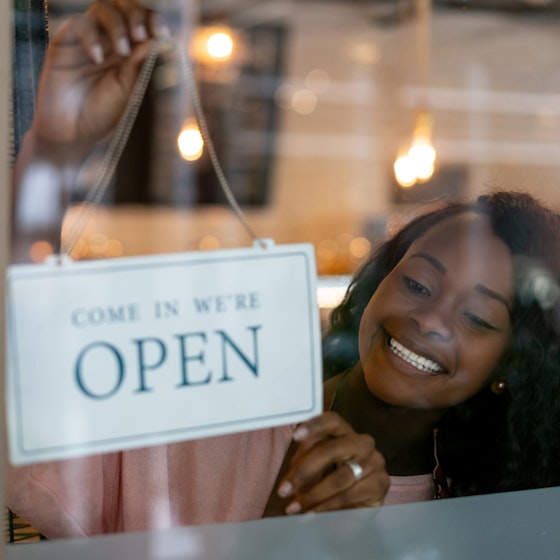 woman holding open sign in business window