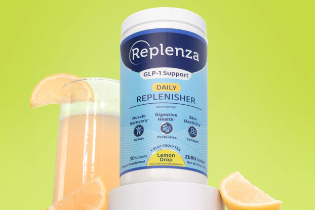 A blue-and-white bottle of Replenza GLP-1 support supplement next to a glass of lemonade and a few lemon slices.