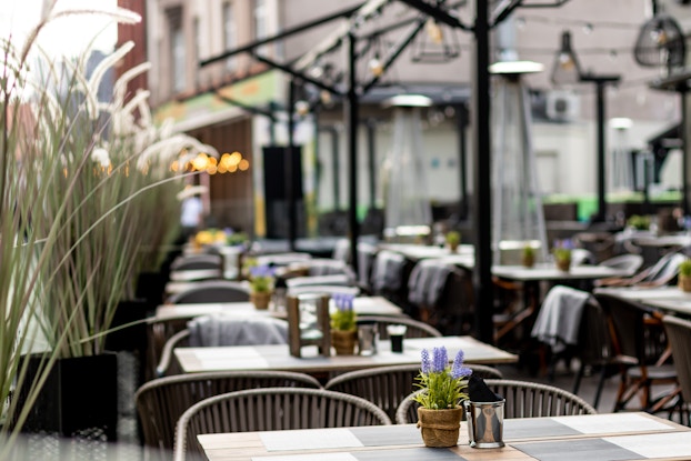 Outdoor restaurant with tables set up waiting for customers to arrive.