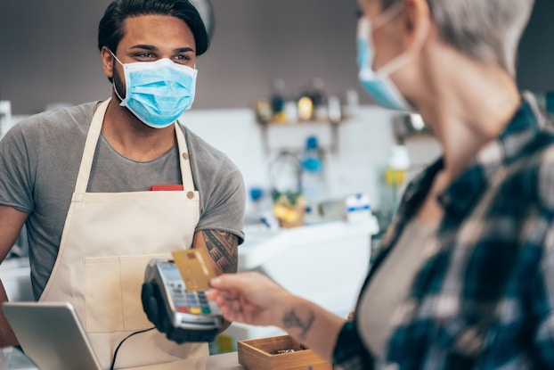 customer paying employee with credit card while wearing masks