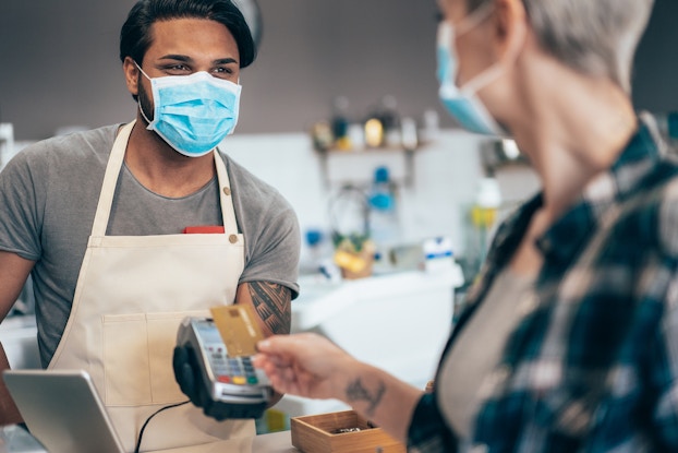  customer paying employee with credit card while wearing masks