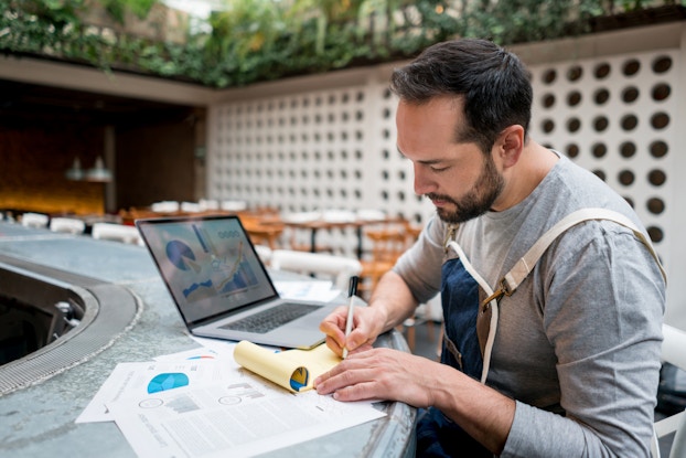 business owner sitting outside doing paperwork