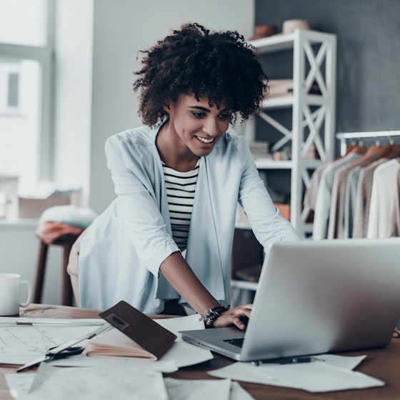 Woman working inside her business on a laptop.