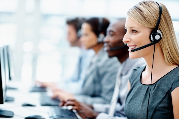 team of salespeople sitting in a row on headsets