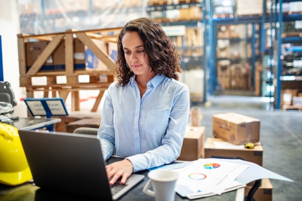  woman working on laptop in warehouse