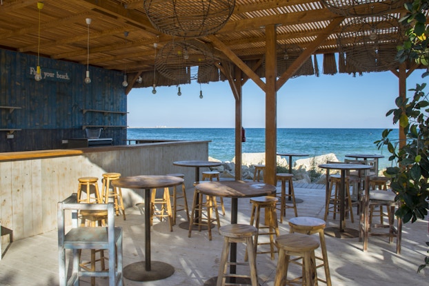  Outdoor beachfront bar with stools, empty and ready for patrons to arrive.