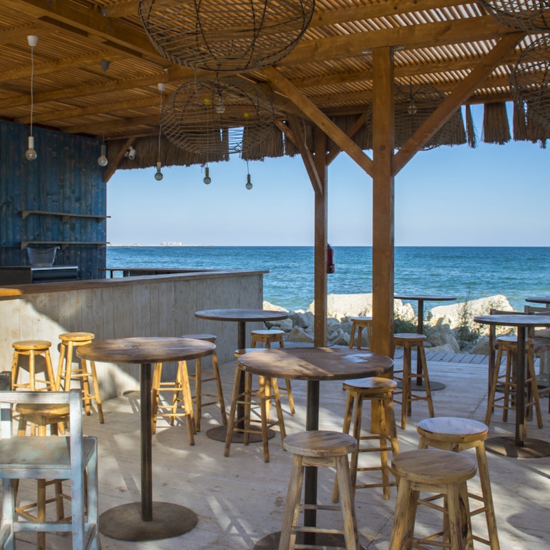  Outdoor beachfront bar with stools, empty and ready for patrons to arrive. 