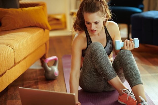  woman exercising at home watching laptop