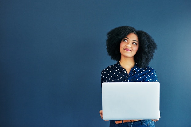  woman smiling and thinking while holding a laptop