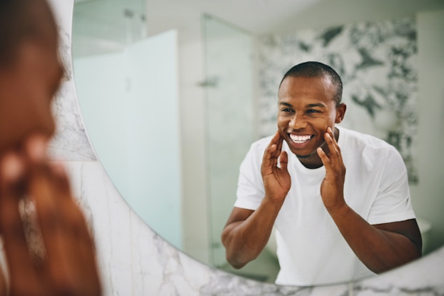  man looking in mirror touching his face
