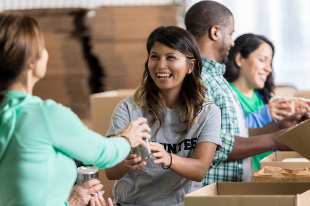  Smiling volunteer accepting canned food at a shelter.