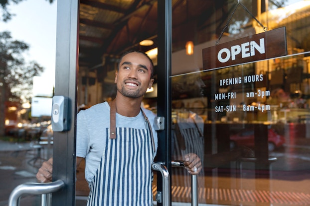  small business owner holding door to business open