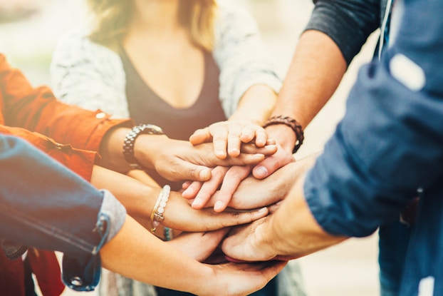  people stacking their hands in a pile