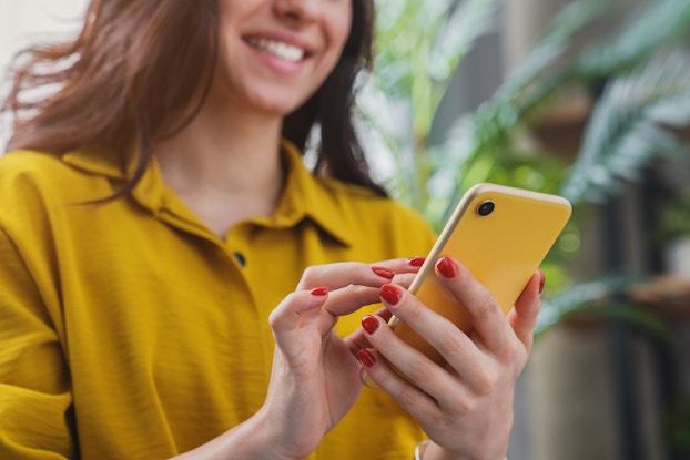  Woman smiling while looking at phone.