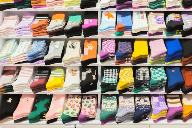  Various multicolored, multipatterned socks are shown stacked on shelves in a store.