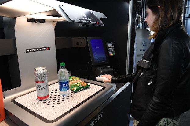  woman purchasing food and drink at clear kiosk in stadium