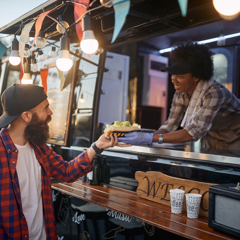 Customer purchasing food from the owner of a food truck.
