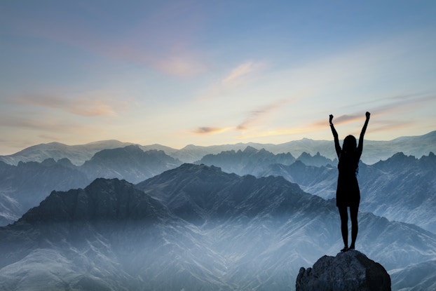  woman standing on top of a mountain with her arms up