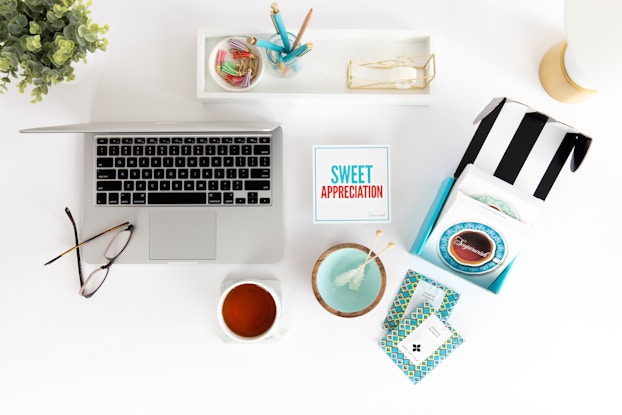 Products from Sugarwish laid out on a white desk next to a laptop.